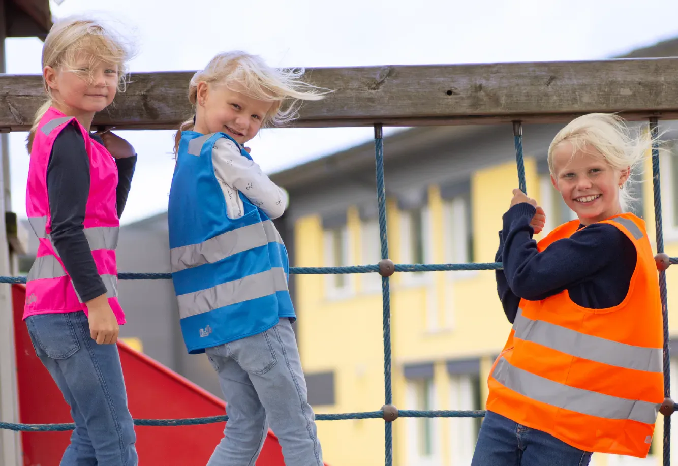 bilde av tre jenter som klatrer i klatrestativ med refleksvester i ulike farger